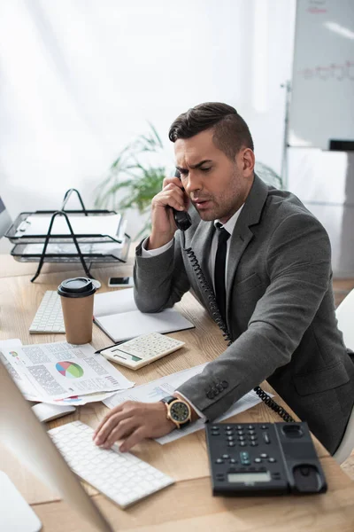 Serious Businessman Talking Telephone While Typing Computer Keyboard Blurred Foreground — Stock Photo, Image