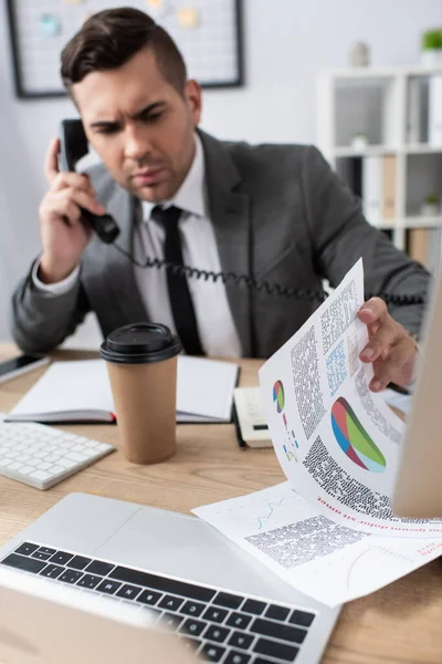 Üzletember Beszél Vezetékes Telefonon Miközben Nézi Papírok Infografika Homályos Háttér — Stock Fotó