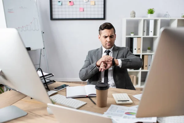 Zakenman Kijkt Naar Polshorloge Terwijl Hij Het Werk Zit Wazig — Stockfoto