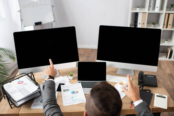 overhead view of trader pointing with fingers at monitors with blank screen 