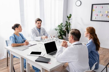 Klinikte evrak ve cihazlarla çalışan çok kültürlü doktorlar ve hemşireler. 