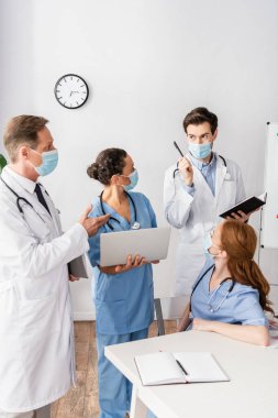 Fikir sahibi doktor, iş yerinin yakınında çok ırklı meslektaşlarının yanında duruyor.
