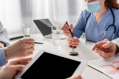İş yerindeki iş arkadaşlarının yanında dijital tabletli hemşire görüntüsü hastanede dizüstü bilgisayar ve beyin anatomik modeli