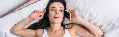 young brunette woman talking on smartphone in bed, banner clipart