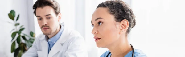 African American Nurse Looking Away Doctor Blurred Background Clinic Banner — Stock Photo, Image