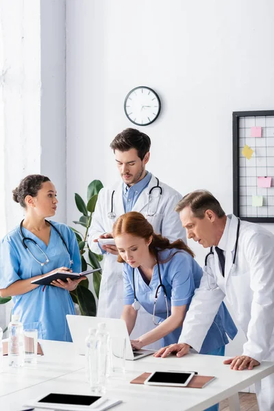 Equipe Hospital Multicultural Trabalhando Com Dispositivos Perto Pastas Papel Água — Fotografia de Stock