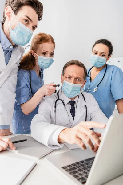 Multiculturele Artsen Verpleegkundigen Medische Maskers Wijzen Naar Laptop Tafel Met — Stockfoto