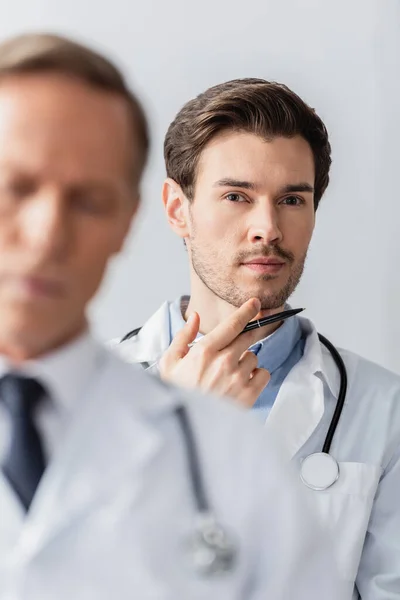 Retrato Del Médico Reflexivo Con Pluma Durante Reunión Con Colega —  Fotos de Stock