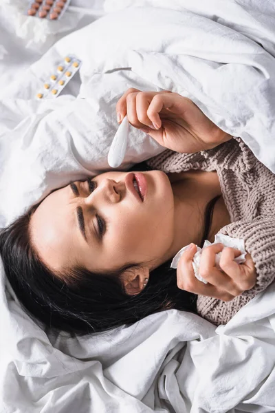 Ovanifrån Sjuk Ung Brunett Kvinna Med Vävnad Och Termometer Sängen — Stockfoto