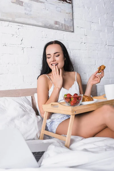 Sonriente Joven Morena Mujer Desayunando Cama Mientras Película Ordenador Portátil — Foto de Stock