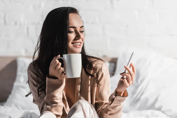 Happy Young Brunette Woman Sitting Bed Mug Smartphone Morning — Stock Photo, Image