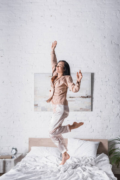young brunette woman jumping in bed at morning