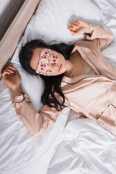 top view of young brunette woman sleeping in bed in sleep mask