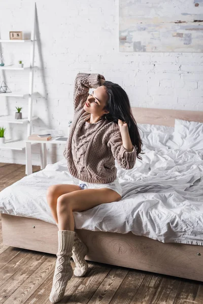 若いブルネットの女性にセーターと靴下でベッドの上に朝座って — ストック写真
