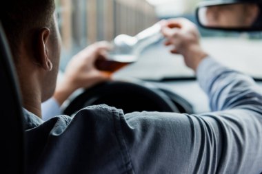 Arabada içki şişesi açan adamın kısmi görüntüsü, bulanık ön plan