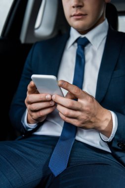 Genç bir iş adamının arabasındaki bulanık arka planda akıllı telefonun görüntüsü.