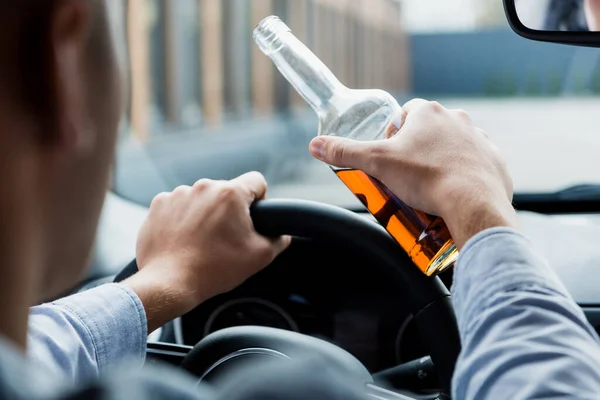 Częściowy Widok Człowieka Jazdy Samochodem Trzymając Butelkę Whisky Zamazany Pierwszy — Zdjęcie stockowe