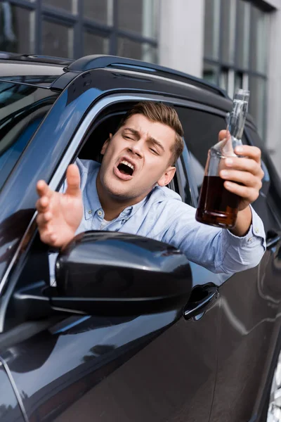 Яний Сердитий Чоловік Пляшкою Алкоголю Жестикулює Кричить Дивлячись Вікно Автомобіля — стокове фото
