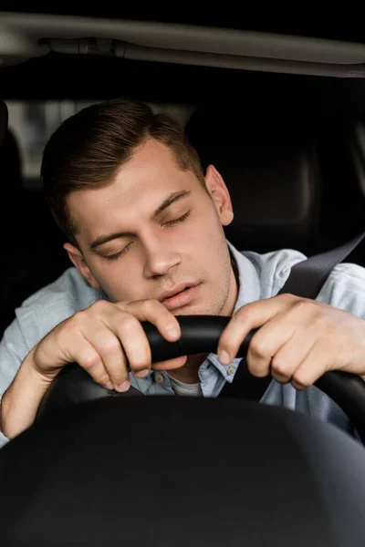 手前の車のハンドルで寝てる酔った男が — ストック写真