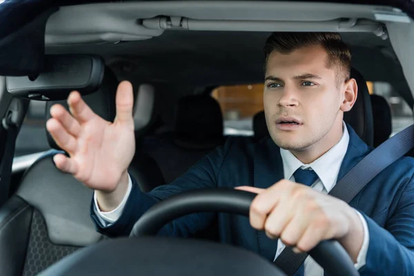 Zakenman Wijzen Met Hand Tijdens Het Rijden Auto Wazig Voorgrond — Stockfoto