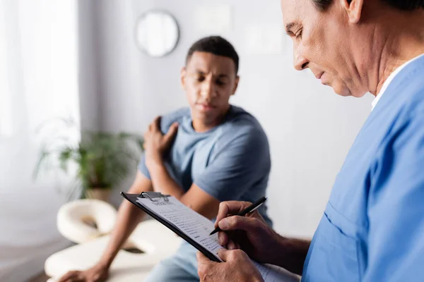 Doctor Escribiendo Prescripción Cerca Afroamericano Paciente Fondo Borroso — Foto de Stock