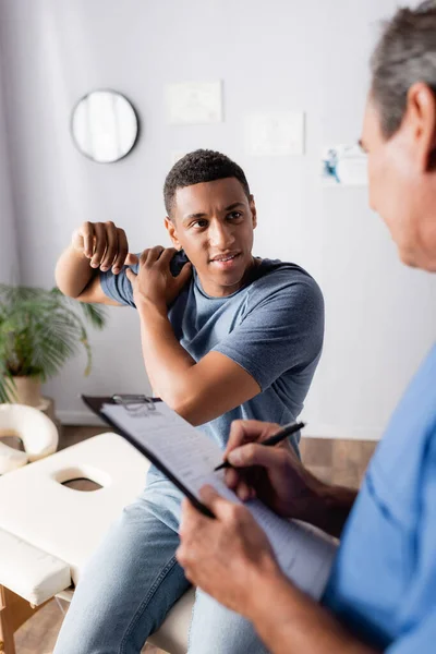 Blessé Homme Afro Américain Regardant Médecin Avec Presse Papiers — Photo