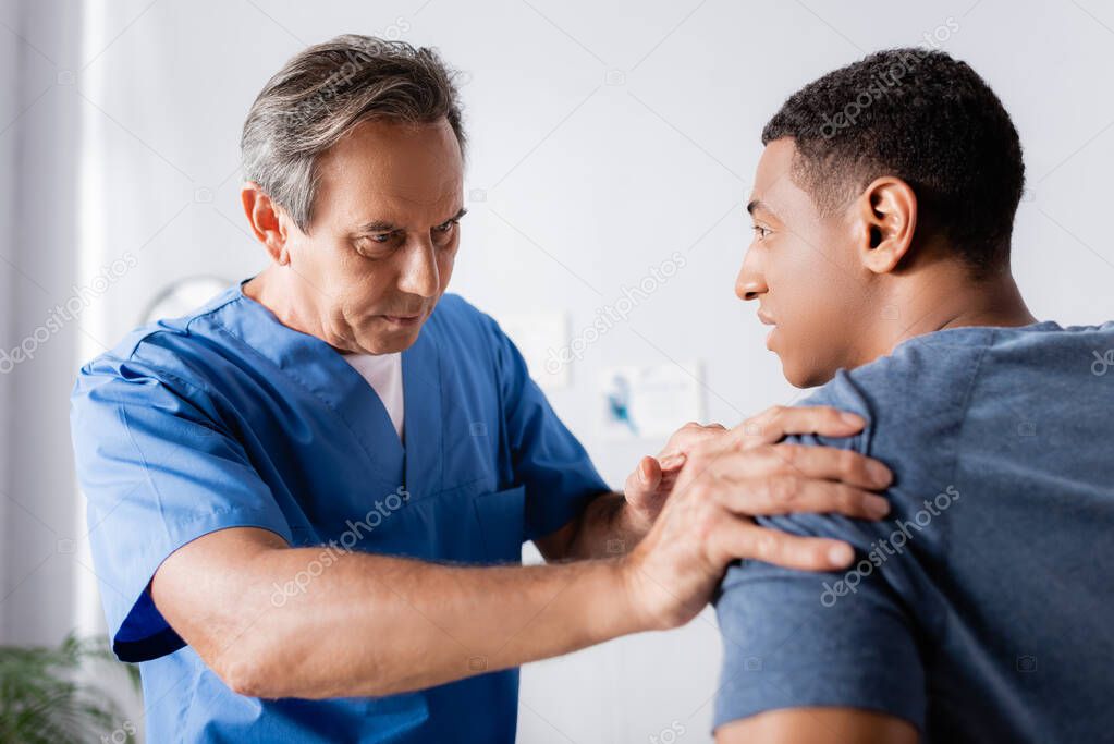 chiropractor working with injured arm of african american patient