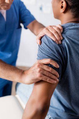 Yaralı Afro-Amerikan bir adamla klinikte çalışan kayropraktik uzmanının kısmi görüntüsü