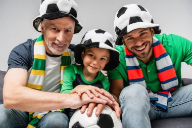 Taraftar şapkalı mutlu erkekler ve çocuklar, Grey 'de izole edilmiş futbol şampiyonası izliyorlar.