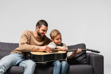 Mutlu baba oğluna akustik gitar çalmayı öğretiyor.