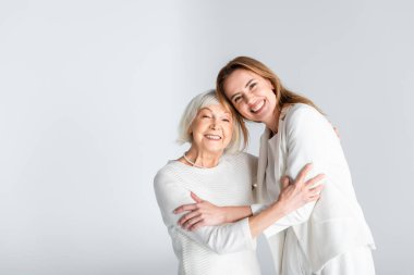 Yaşlı annenin mutlu kızıyla kucaklaşması gri renkte izole edilmiş. 