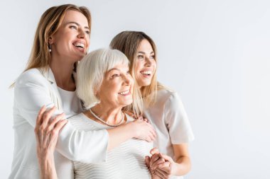 three generation of positive women smiling while hugging isolated on white clipart