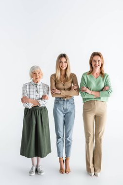 Üç kuşak boyunca mutlu kadınlar gülümserken kolları çapraz beyaz dururlar.