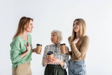 three generation of women holding paper cups and arguing isolated on white clipart