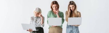 Beyaz pankartta izole edilmiş dizüstü bilgisayar kullanan üç nesil düşünceli kadın.