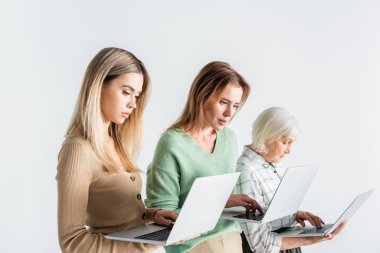 Beyaz dizüstü bilgisayar kullanan üç nesil kadın.