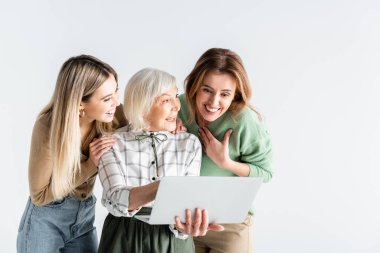 Dizüstü bilgisayara bakan üç nesil mutlu kadın beyaza izole edilmiş.
