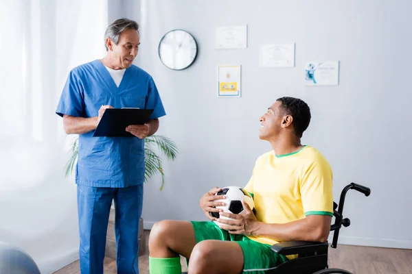 Discapacitado Afroamericano Deportista Silla Ruedas Celebración Fútbol Sonriendo Cerca Médico — Foto de Stock