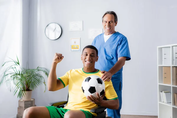 Cheerful African American Sportsman Wheelchair Holding Football Smiling Doctor — Stock Photo, Image