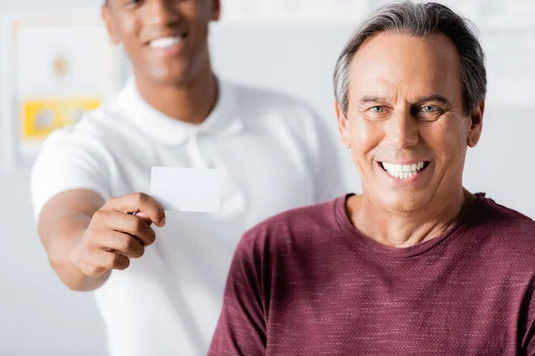 Homem Feliz Sorrindo Perto Terapeuta Americano Africano Alegre Segurando Cartão — Fotografia de Stock