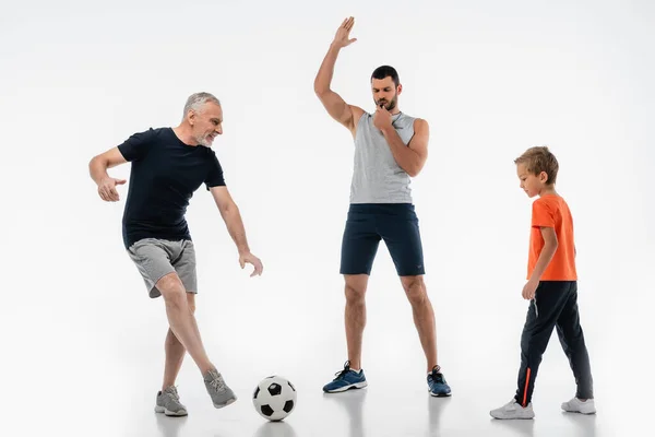 Mann Sportkleidung Pfeift Neben Opa Fußball Mit Enkel Auf Weiß — Stockfoto