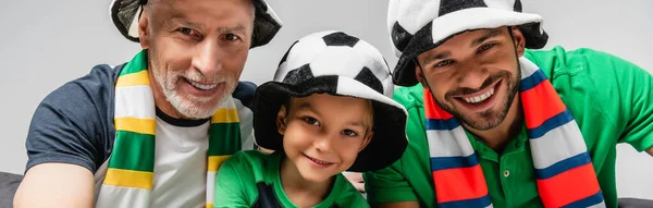 happy men and boy in fan hats watching football championship isolated on grey, banner