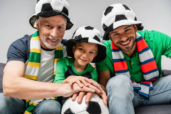 happy men and boy in fan hats watching football championship isolated on grey