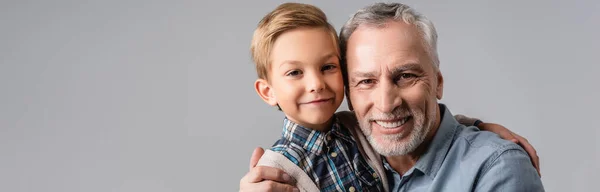Szczęśliwy Dziadek Wnuk Przytula Się Podczas Uśmiechu Kamery Odizolowany Szary — Zdjęcie stockowe