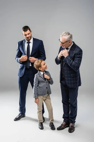 面带微笑的商人看着祖父和孙子摸灰色领带 — 图库照片