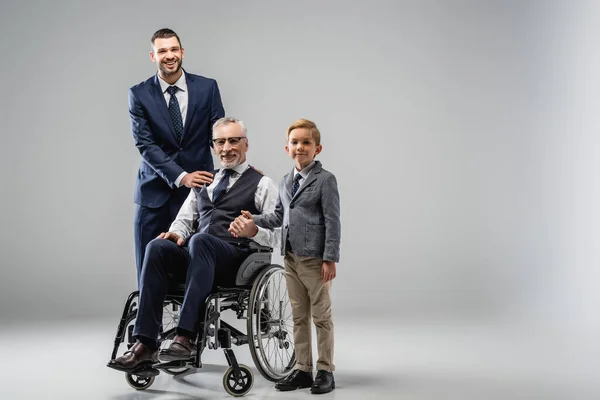 Hombre Feliz Silla Ruedas Cerca Hijo Nieto Sonriendo Cámara Gris — Foto de Stock