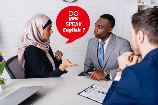 arabian businesswoman pointing with hand near contract and interracial business partners, speech bubble with do you speak english illustration