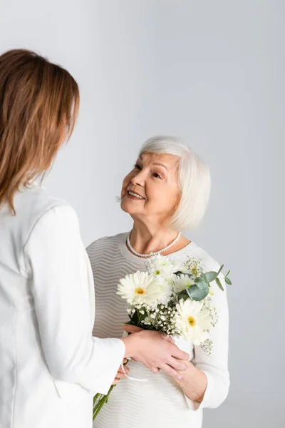 Datter Giver Blomster Til Glad Senior Mor Isoleret Grå - Stock-foto