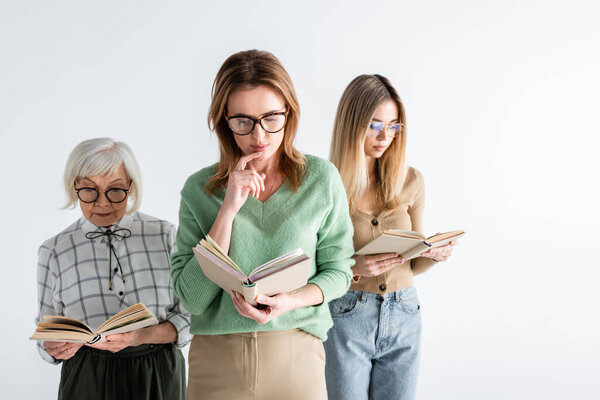 three generation of intelligent women in glasses reading books isolated on white