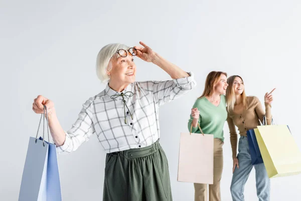 Happy Senior Woman Shopping Bag Adjusting Glasses Daughter Granddaughter Blurred — Stock Photo, Image